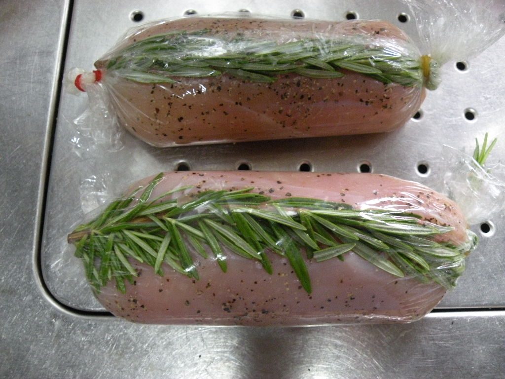 塩麴に漬けておいた鶏肉を巻き、表面に黒こしょうをふってローズマリーをのせ、ラップを巻き、両端を輪ゴムで留めてキャンディ状に包む。