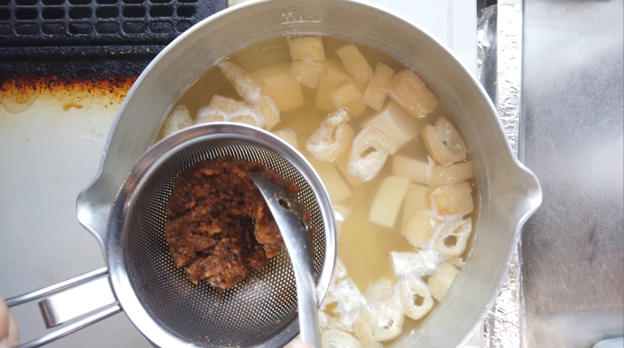 【豆腐と油揚げの味噌汁の作り方】４．出汁に（3）を加えて温め、火を止めて味噌を溶かす。