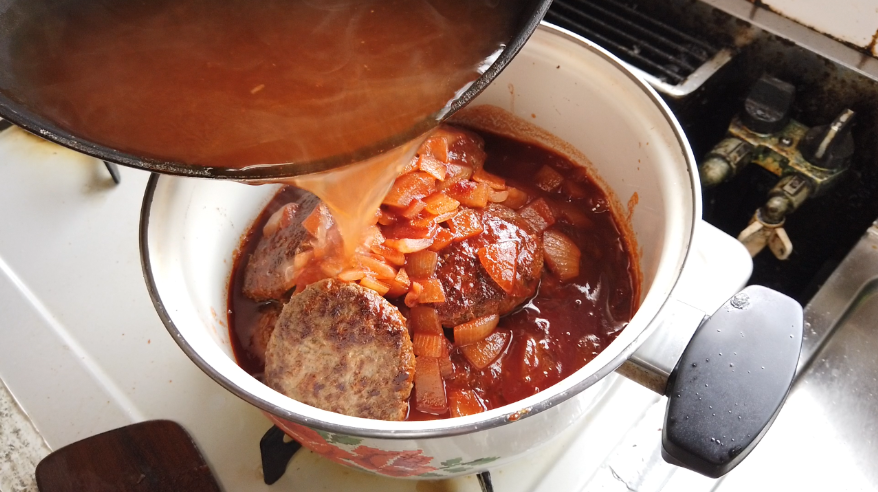 【煮込みハンバーグレシピ】７．移したらフライパンに水を加えて煮立たせ、フライパンの底をこそぐようにして、旨みを残さず煮込み用の鍋に移します。