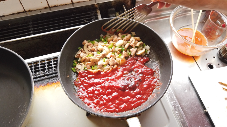 【オムライスレシピ】５．炒めたものをフライパンの端に置いて、ケチャップを加え、酸味が飛んで香りが立ってくるまで炒めたら、ウスターソースを加え、炒めたものと混ぜ合わせます。
