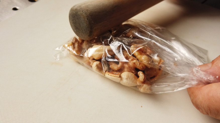 【春菊サラダレシピ】２．カシューナッツとクルミを煎り、少し冷めてからビニール袋に入れて、棒で軽く砕きます。